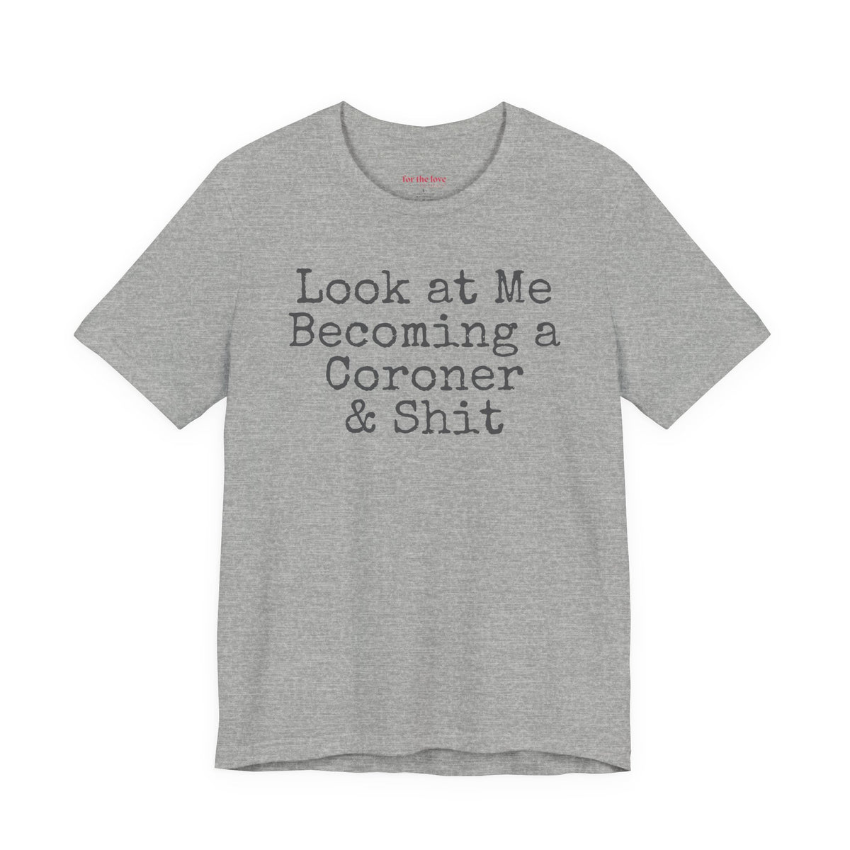Grey funny coroner T-shirt featuring the phrase Look at Me Becoming a Coroner & Shit in vintage typewriter-style lettering.