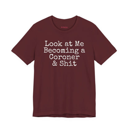 Marron funny coroner T-shirt featuring the phrase Look at Me Becoming a Coroner & Shit in vintage typewriter-style lettering.