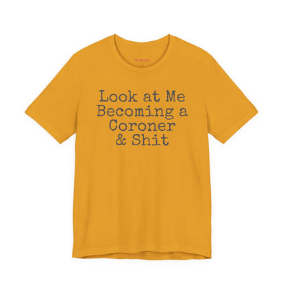 mustard funny coroner T-shirt featuring the phrase Look at Me Becoming a Coroner & Shit in vintage typewriter-style lettering.