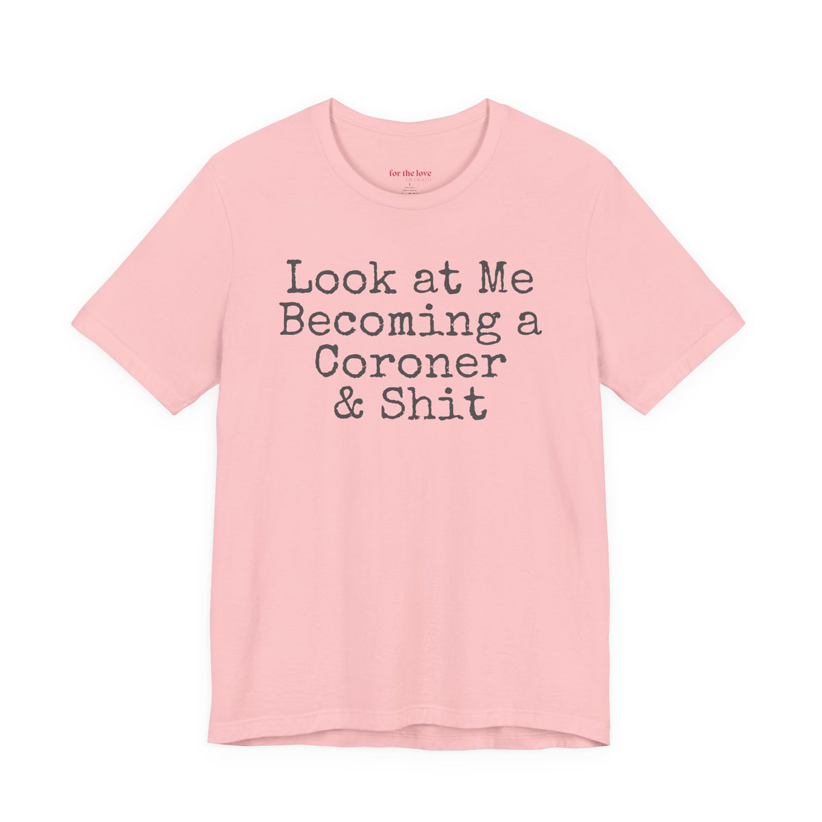 Pink funny coroner T-shirt featuring the phrase Look at Me Becoming a Coroner & Shit in vintage typewriter-style lettering.