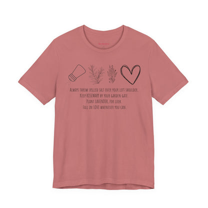 pink graphic t-shirt featuring rosemary, lavender, salt, and heart illustrations with a practical magic inspired quote