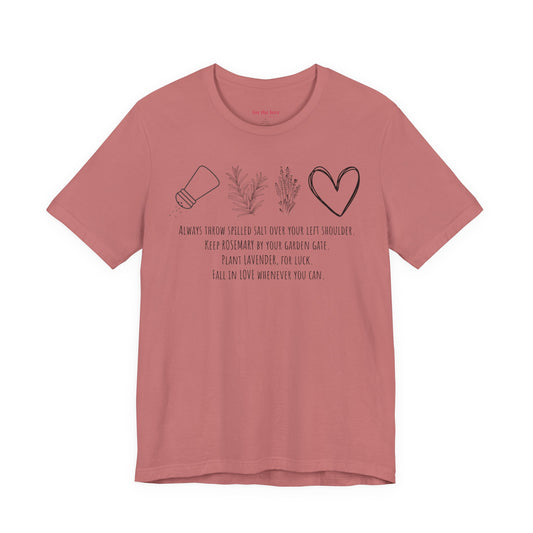 pink graphic t-shirt featuring rosemary, lavender, salt, and heart illustrations with a practical magic inspired quote